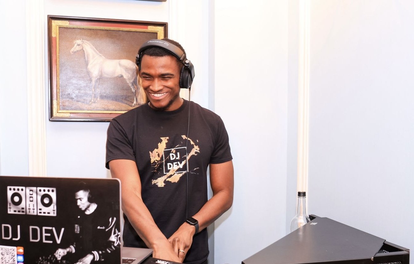 DJ Dev smiling behind the decks at a private party